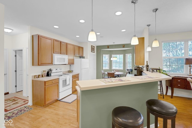 575 Dylan Dr, Avon, IN 46123 - kitchen featuring white appliances, a kitchen bar, light wood-style floors, recessed lighting, and hanging light fixtures