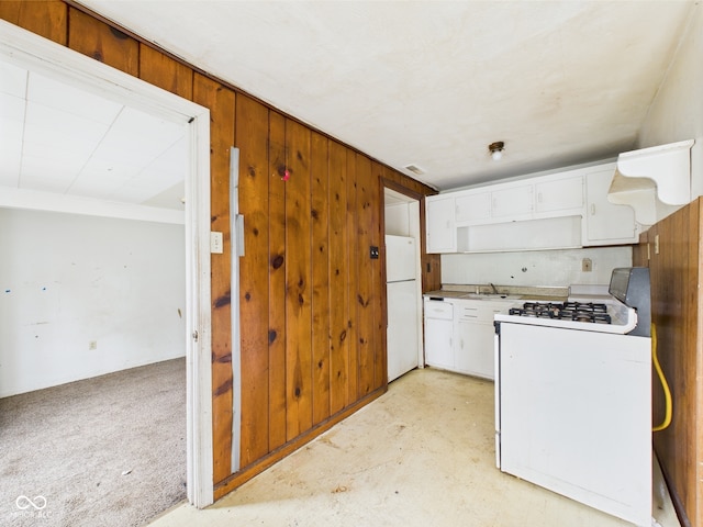 29 E Pine St, Anderson, IN 46012 - kitchen with white appliances, white cabinetry, wood walls, a sink, and light countertops