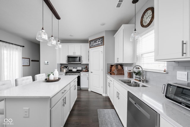 2542 Barstow Dr, Whitestown, IN 46075 - kitchen featuring stainless steel appliances, a sink, backsplash, a center island, and white cabinetry