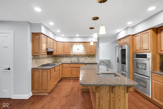 10602 Fall Rd, Fishers, IN 46037 - kitchen with stainless steel appliances, a sink, wood finished floors, under cabinet range hood, and dark stone counters