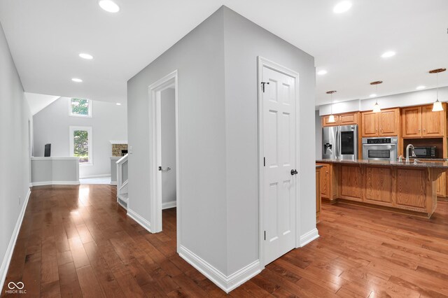 10602 Fall Rd, Fishers, IN 46037 - kitchen featuring stainless steel appliances, dark wood-type flooring, a breakfast bar, stone counters, and hanging light fixtures