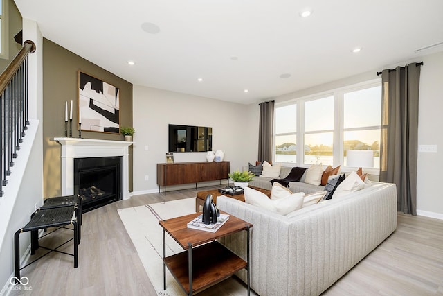 living room with stairs, light wood finished floors, recessed lighting, a fireplace, and baseboards