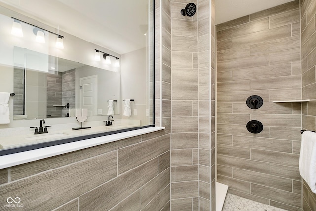bathroom with a tile shower and double vanity