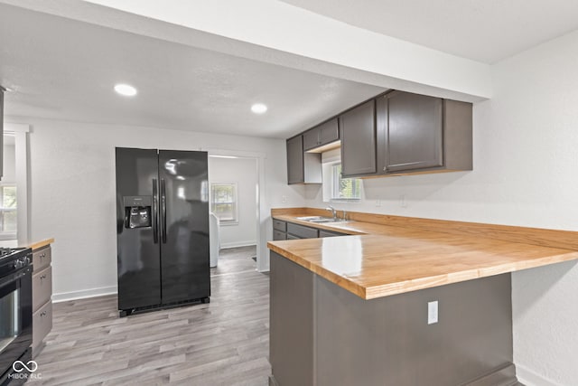 2321 W 26th St, Anderson, IN 46016 - kitchen with black appliances, a sink, light wood finished floors, wooden counters, and a peninsula