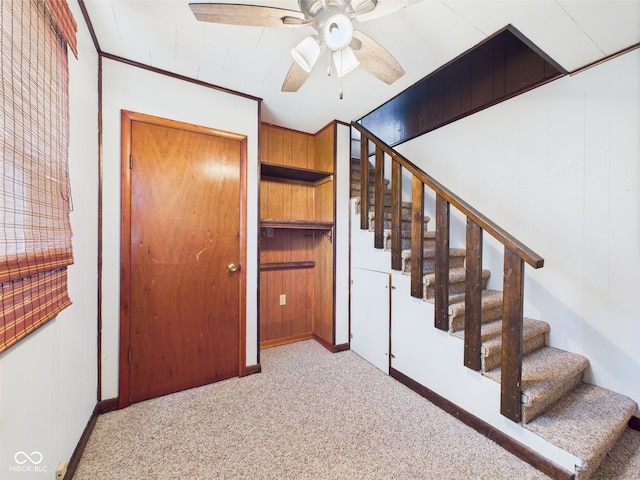 stairway with carpet flooring, a ceiling fan, and baseboards