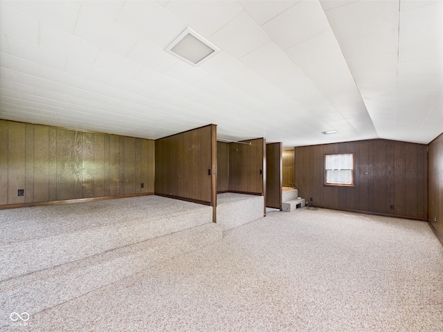 additional living space featuring wooden walls, light colored carpet, and lofted ceiling