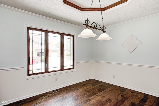 spare room with a textured ceiling, dark wood-style floors, crown molding, baseboards, and a raised ceiling