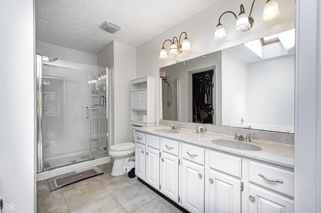 bathroom featuring a skylight, toilet, a shower stall, double vanity, and tile patterned flooring