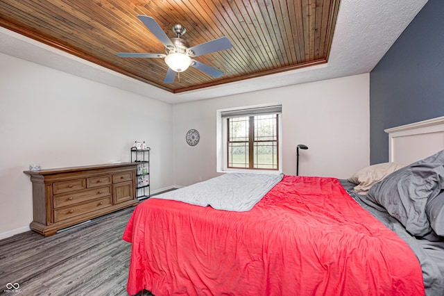 bedroom with wood ceiling, a raised ceiling, wood finished floors, baseboards, and a ceiling fan