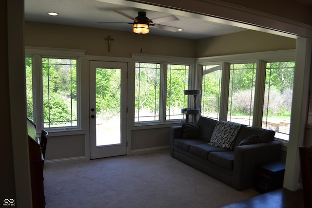 living area with a ceiling fan, healthy amount of natural light, baseboards, and carpet flooring