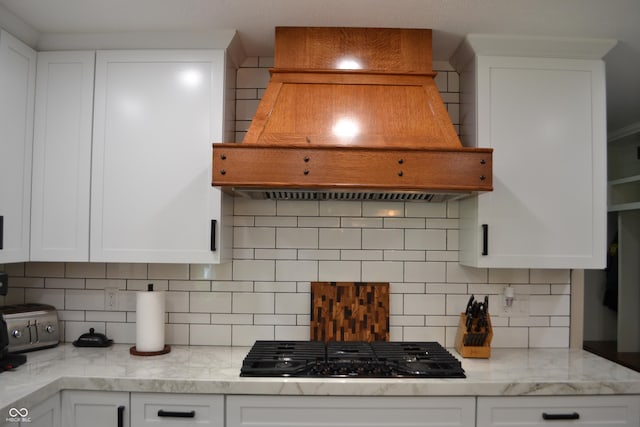 kitchen featuring custom exhaust hood, black gas stovetop, tasteful backsplash, and white cabinets