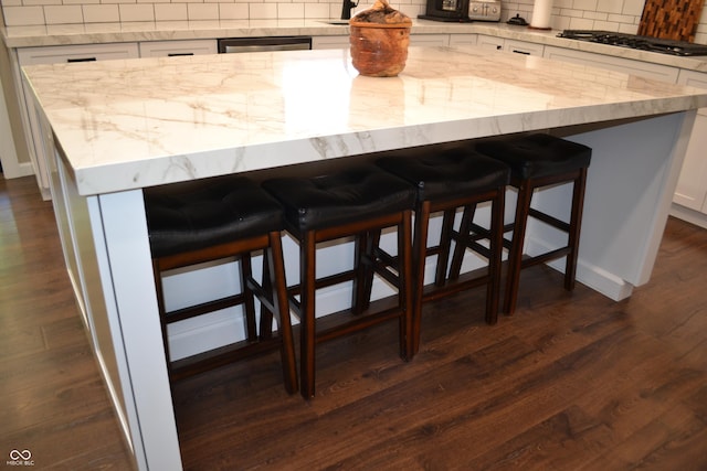 kitchen view of gas cooktop, tasteful backsplash, white cabinetry, and dark wood-type flooring