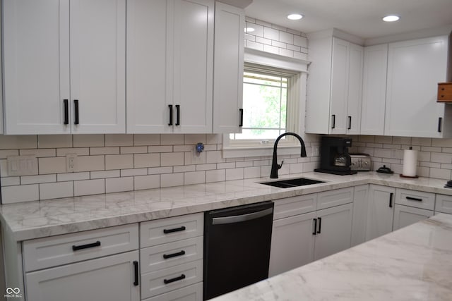 kitchen featuring dishwasher, a sink, white cabinetry, backsplash, and light stone counters
