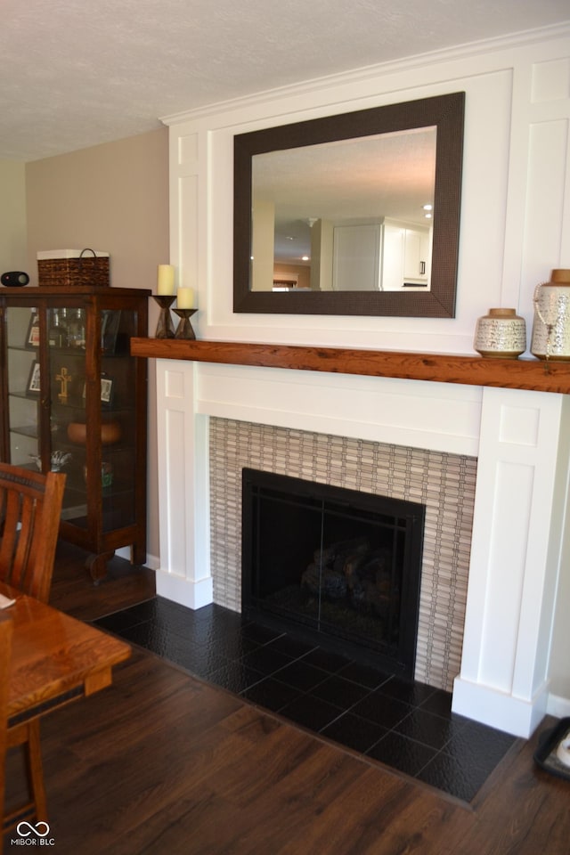 detailed view of a tiled fireplace, wood finished floors, and baseboards