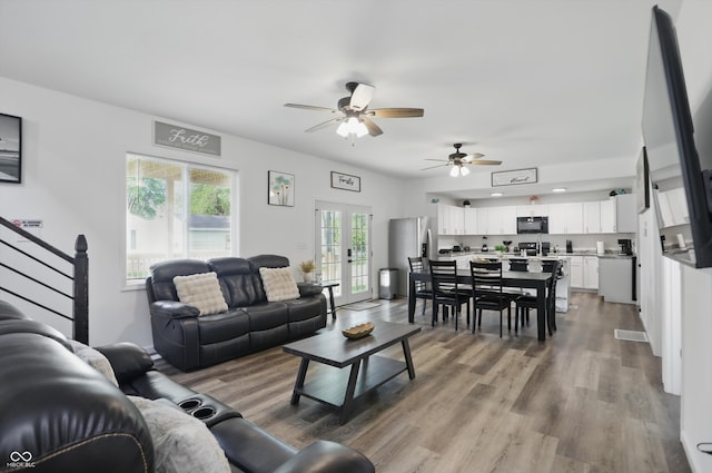 living room featuring healthy amount of natural light, ceiling fan, wood finished floors, and stairs
