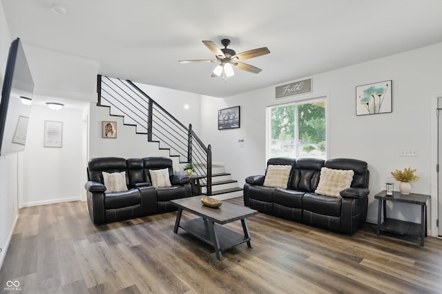 living room featuring wood finished floors, ceiling fan, and stairway