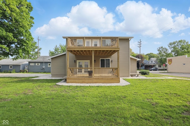 rear view of house with a wooden deck, french doors, and a lawn