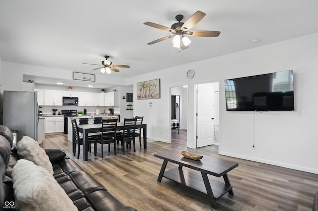 living area with a ceiling fan, baseboards, and light wood finished floors