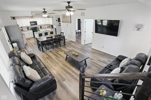 living area featuring a ceiling fan, light wood-style floors, and baseboards