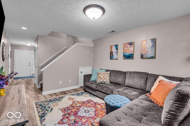 living area with wood finished floors, stairway, a textured ceiling, and baseboards