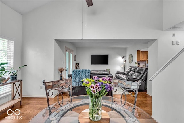living area featuring wood finished floors, a high ceiling, a ceiling fan, and baseboards