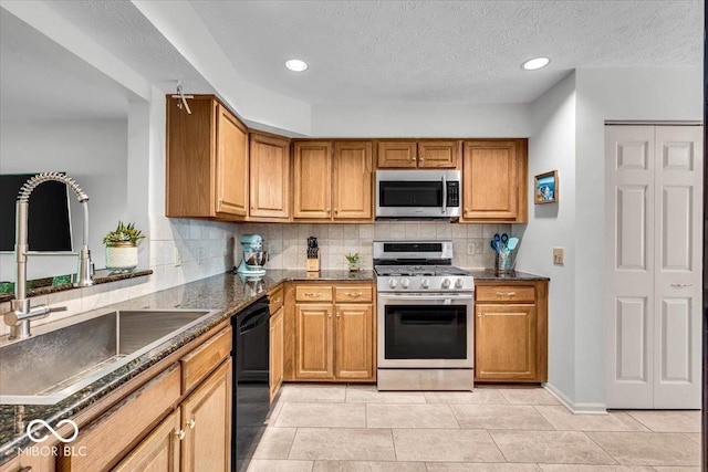 kitchen featuring stainless steel appliances, a sink, brown cabinetry, decorative backsplash, and light tile patterned floors