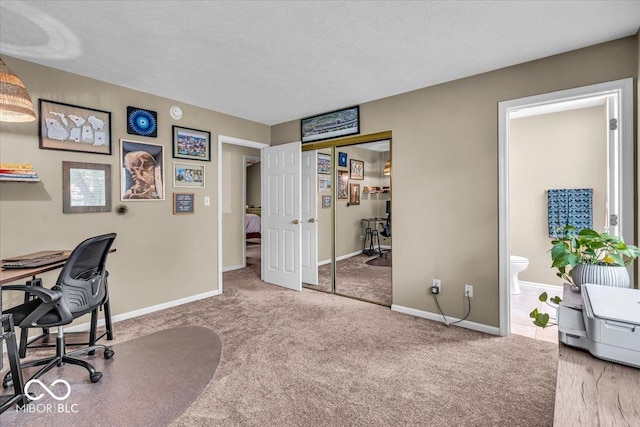 carpeted office with baseboards and a textured ceiling