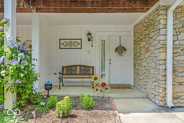 view of exterior entry featuring stone siding and covered porch