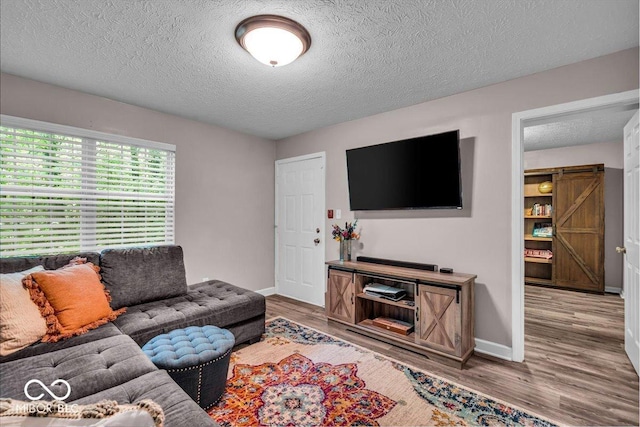 living room featuring a textured ceiling, baseboards, and wood finished floors