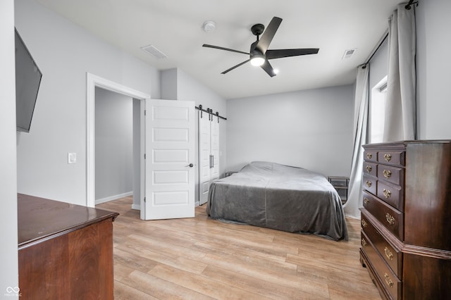 141 W 10th St, Seymour, IN 47274 - bedroom with a barn door, light wood-type flooring, and ceiling fan