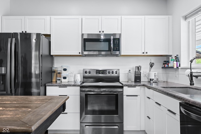 141 W 10th St, Seymour, IN 47274 - kitchen featuring stainless steel appliances, a sink, white cabinets, and dark stone countertops