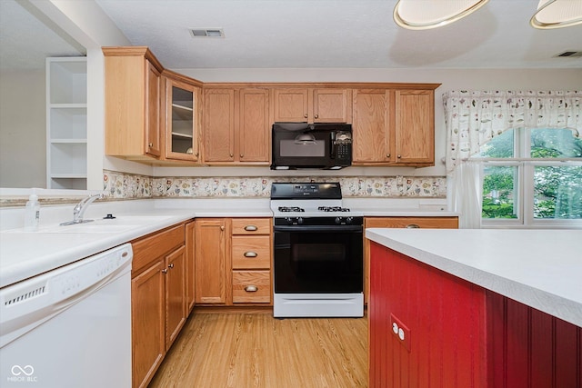 10833 Tournament Ln, Indianapolis, IN 46229 - kitchen with black microwave, dishwasher, gas range, light wood-type flooring, and light countertops