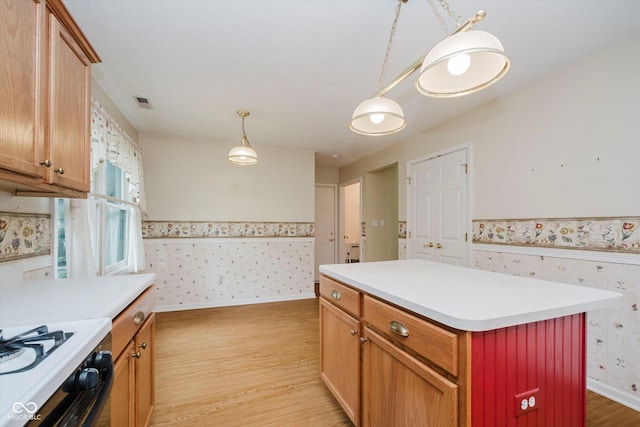 10833 Tournament Ln, Indianapolis, IN 46229 - kitchen featuring wallpapered walls, wainscoting, light wood-type flooring, light countertops, and gas stove