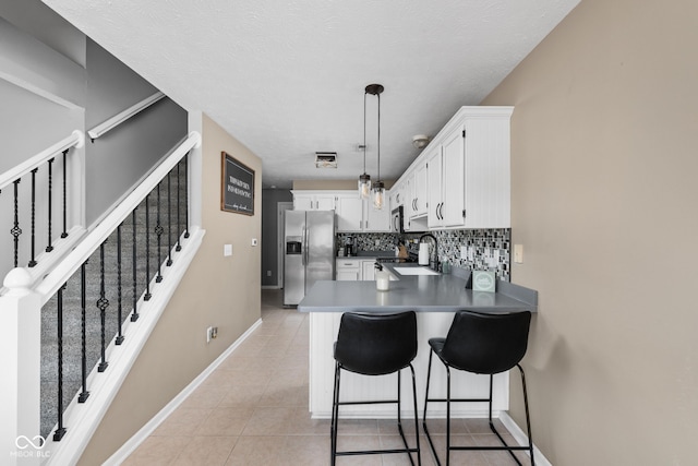 9404 Enclave Dr Unit D, Avon, IN 46123 - kitchen featuring stainless steel refrigerator with ice dispenser, a peninsula, white cabinets, decorative backsplash, and decorative light fixtures