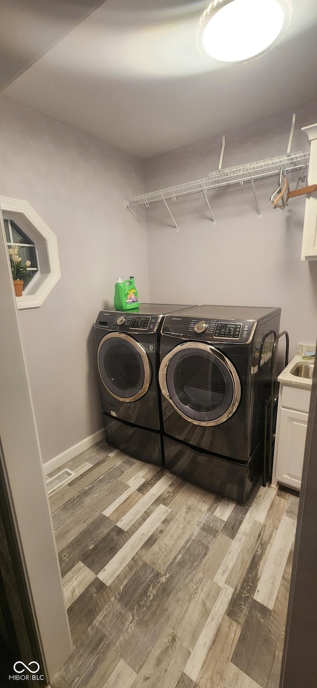 5415 S Chalmers Ct, Bloomington, IN 47403 - laundry area featuring washer and clothes dryer, light wood-type flooring, cabinet space, and baseboards