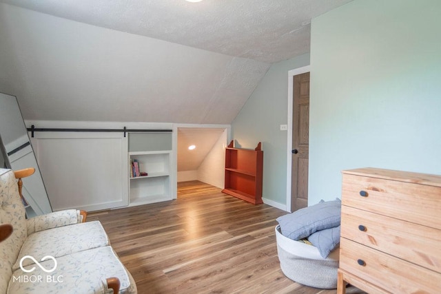 1409 S Northview Dr, Martinsville, IN 46151 - bedroom with lofted ceiling, wood finished floors, a barn door, a textured ceiling, and baseboards