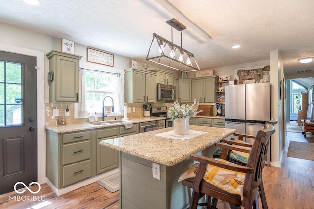 1409 S Northview Dr, Martinsville, IN 46151 - kitchen with stainless steel appliances, a sink, a textured ceiling, a center island, and light wood-style floors