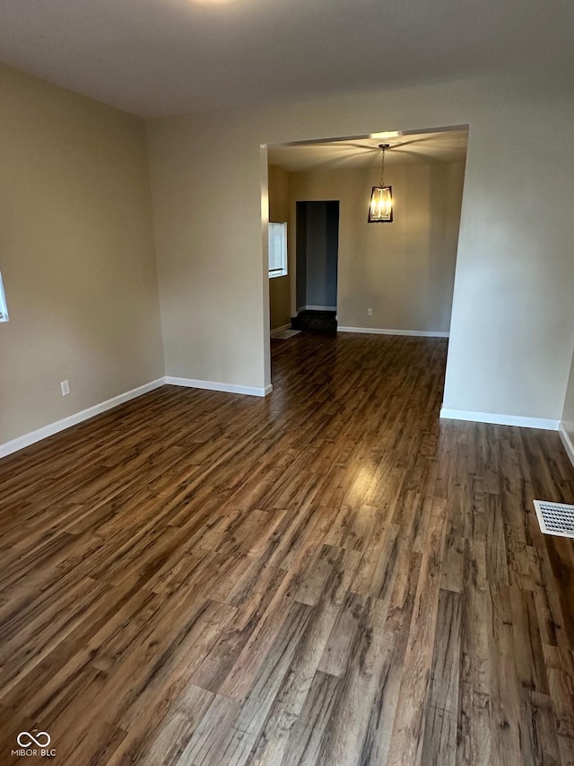 empty room featuring dark wood-type flooring and baseboards
