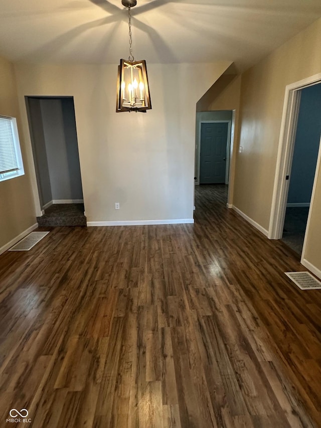 unfurnished dining area with dark wood-type flooring, a chandelier, and baseboards