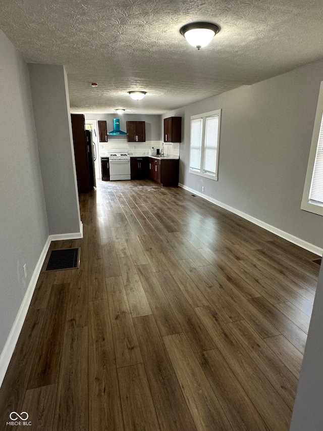 unfurnished living room with dark wood-style floors, a textured ceiling, baseboards, and a sink
