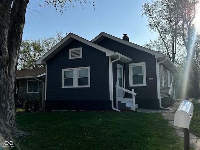 view of front facade featuring entry steps, a chimney, and a front lawn