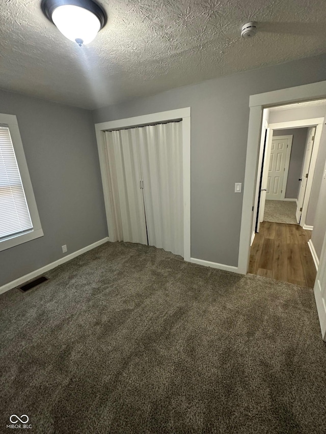 unfurnished bedroom with carpet flooring, a closet, baseboards, and a textured ceiling