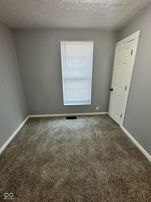 unfurnished room featuring carpet, baseboards, and a textured ceiling