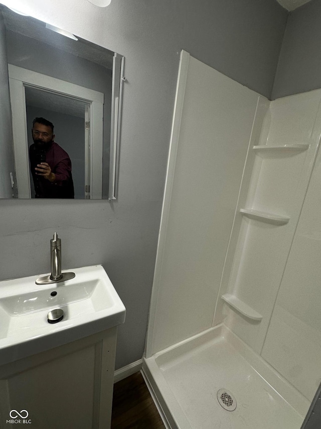 bathroom with a stall shower, vanity, and wood finished floors