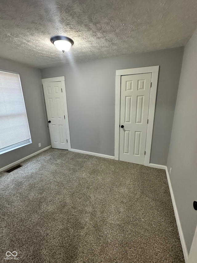 carpeted spare room featuring baseboards and a textured ceiling