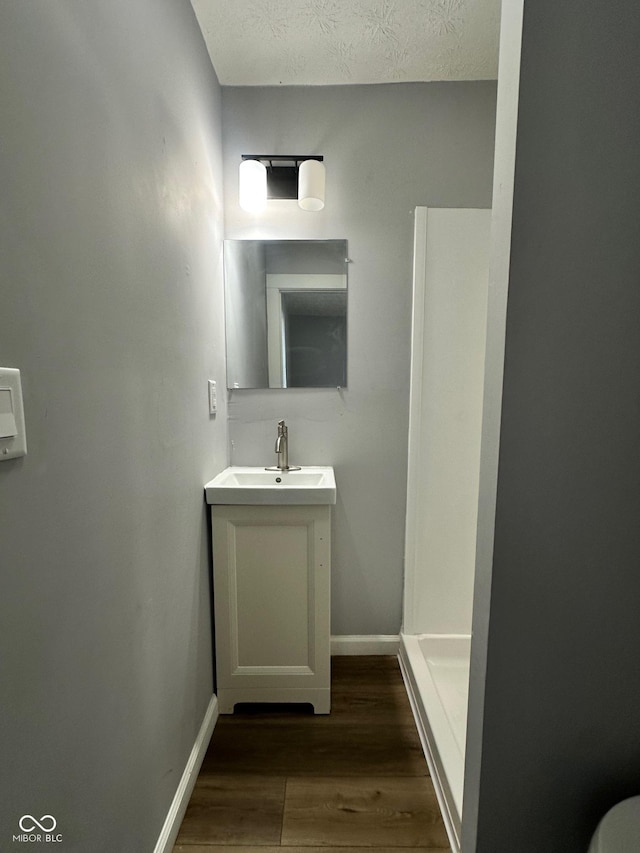 bathroom with wood finished floors, vanity, and baseboards
