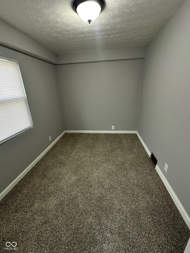 unfurnished room with a textured ceiling, carpet flooring, and baseboards