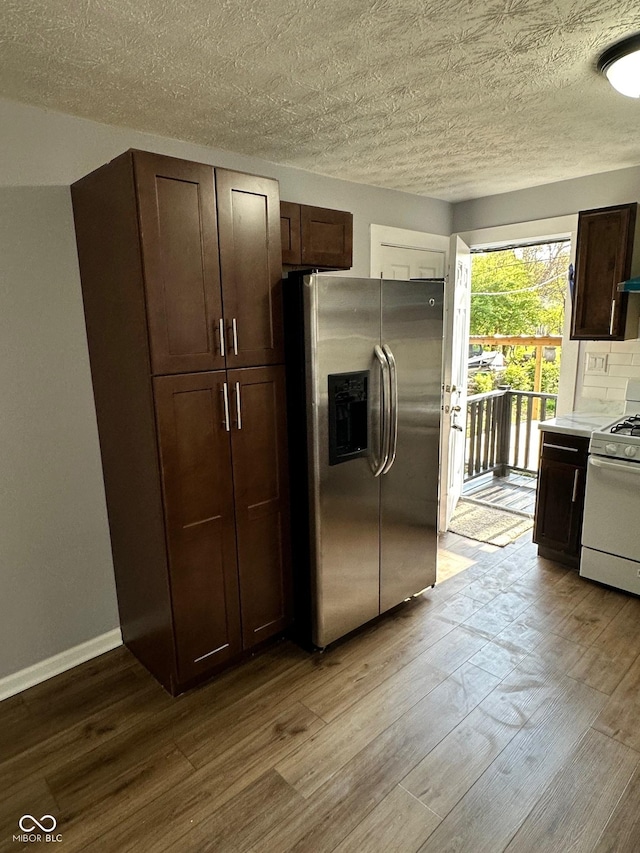 kitchen featuring stainless steel fridge with ice dispenser, gas range gas stove, wood finished floors, dark brown cabinets, and a textured ceiling