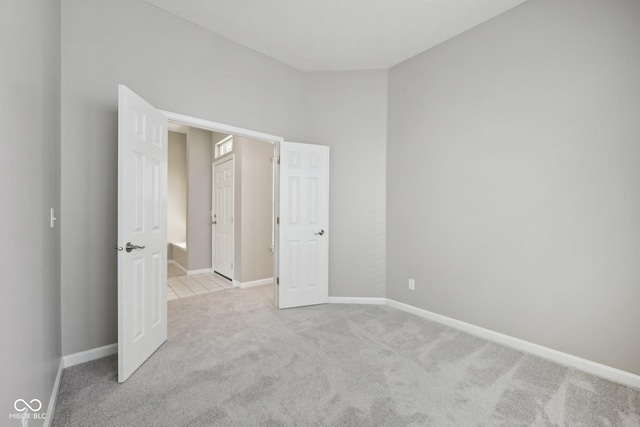 unfurnished bedroom featuring light colored carpet and baseboards