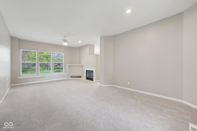 unfurnished living room with carpet, ceiling fan, baseboards, a tile fireplace, and recessed lighting